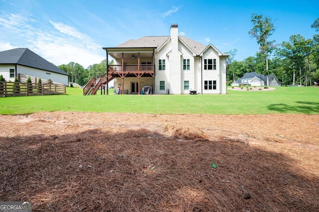 rear view of house featuring ceiling fan, a deck, and a yard