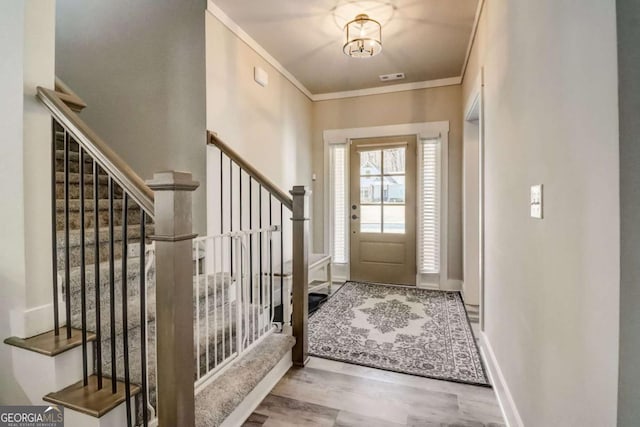 entryway with hardwood / wood-style floors and ornamental molding