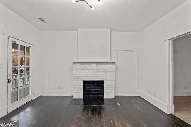 unfurnished living room featuring dark hardwood / wood-style floors, a brick fireplace, and a textured ceiling