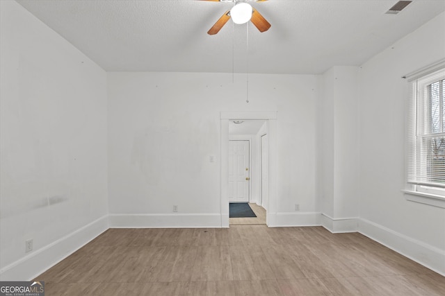 unfurnished room with ceiling fan and a textured ceiling