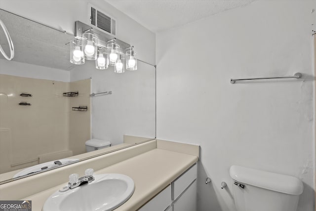 bathroom with vanity, a shower, a textured ceiling, and toilet