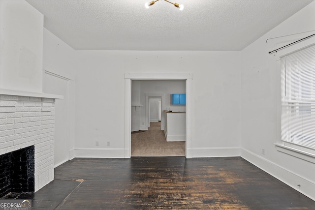 unfurnished living room featuring a brick fireplace, dark hardwood / wood-style floors, and a textured ceiling