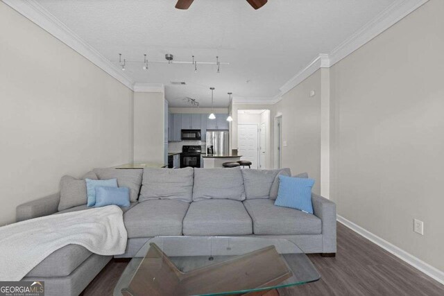 living room with dark hardwood / wood-style flooring, track lighting, ceiling fan, and crown molding