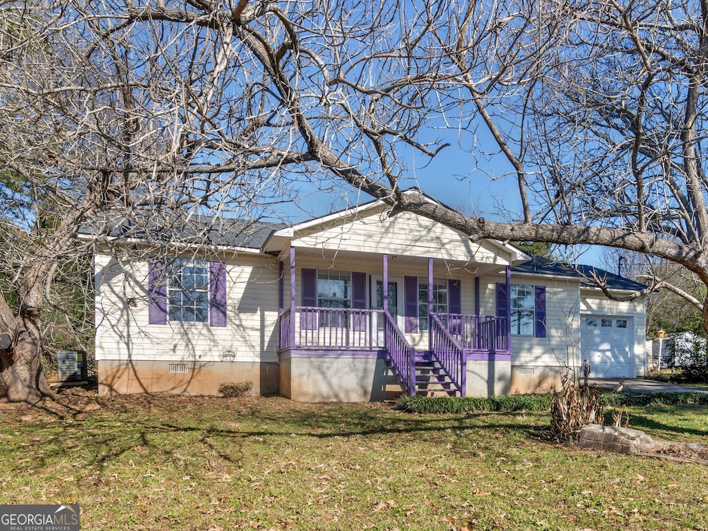 view of front of house featuring a porch, a garage, and a front lawn