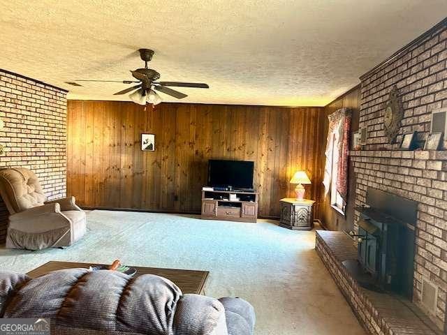 living room featuring wood walls, ceiling fan, and a textured ceiling