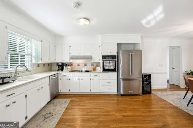 kitchen with white cabinets, appliances with stainless steel finishes, and light hardwood / wood-style flooring