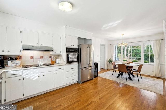 kitchen with black appliances, decorative backsplash, pendant lighting, and white cabinets