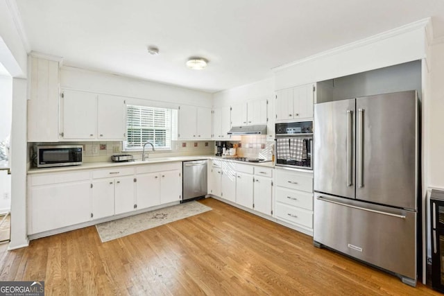 kitchen featuring appliances with stainless steel finishes, tasteful backsplash, sink, light hardwood / wood-style flooring, and white cabinets