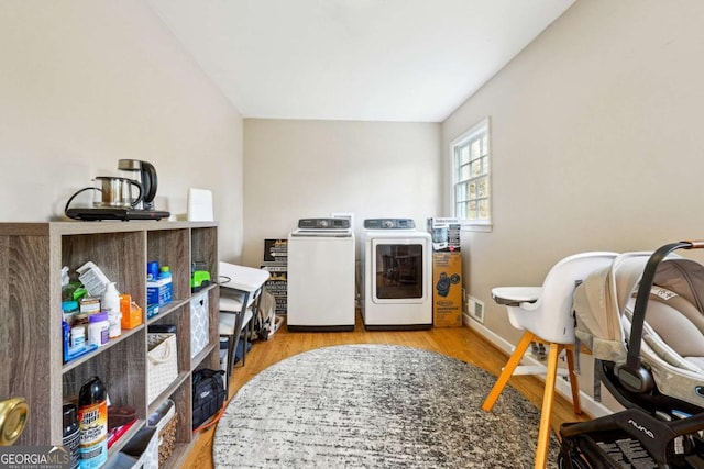 laundry room featuring separate washer and dryer and light hardwood / wood-style flooring