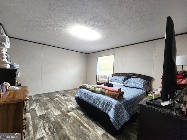 bedroom with cooling unit, a textured ceiling, and hardwood / wood-style flooring