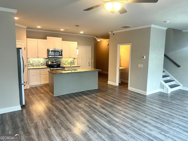 kitchen with a kitchen island with sink, dark stone counters, white cabinets, dark hardwood / wood-style floors, and appliances with stainless steel finishes