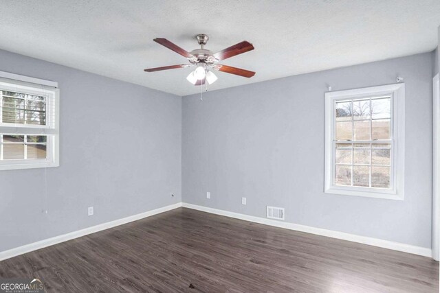 spare room with a textured ceiling, ceiling fan, and dark wood-type flooring