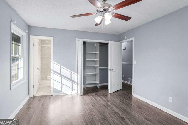 unfurnished bedroom featuring ensuite bath, ceiling fan, dark hardwood / wood-style floors, a textured ceiling, and a closet