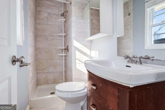 bathroom featuring vanity, toilet, and a tile shower