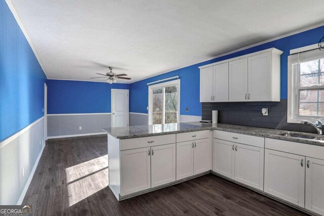 kitchen featuring white cabinetry, sink, light stone counters, backsplash, and kitchen peninsula