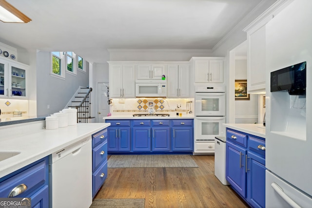 kitchen featuring blue cabinetry, backsplash, white appliances, white cabinets, and hardwood / wood-style flooring