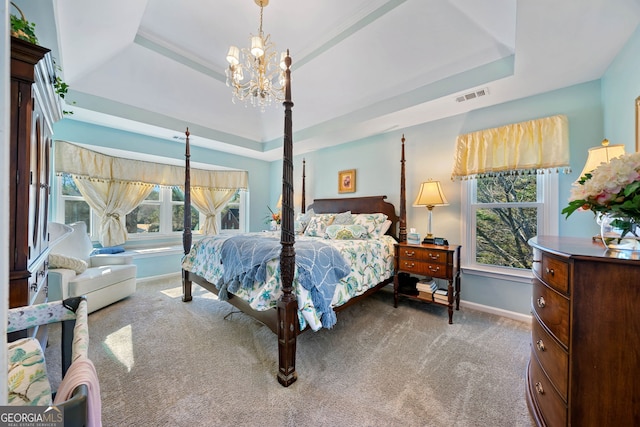 carpeted bedroom featuring a raised ceiling, multiple windows, and an inviting chandelier