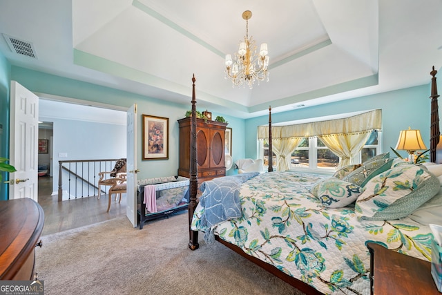 bedroom with carpet, a tray ceiling, and a notable chandelier