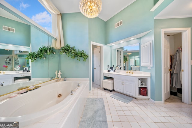 bathroom with a skylight, an inviting chandelier, tile patterned flooring, tiled tub, and vanity