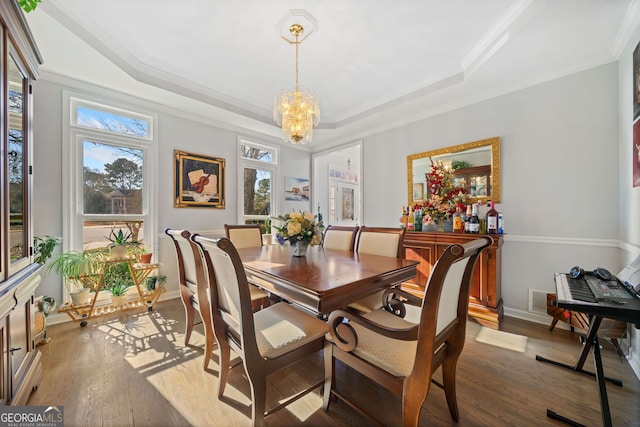 dining space featuring a notable chandelier, dark hardwood / wood-style flooring, crown molding, and a tray ceiling