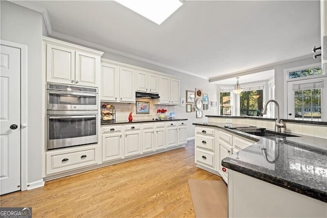 kitchen featuring dark stone countertops, white cabinetry, sink, and ornamental molding