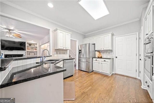 kitchen featuring kitchen peninsula, sink, white cabinets, and stainless steel appliances