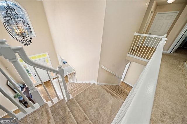 stairs featuring carpet flooring and an inviting chandelier