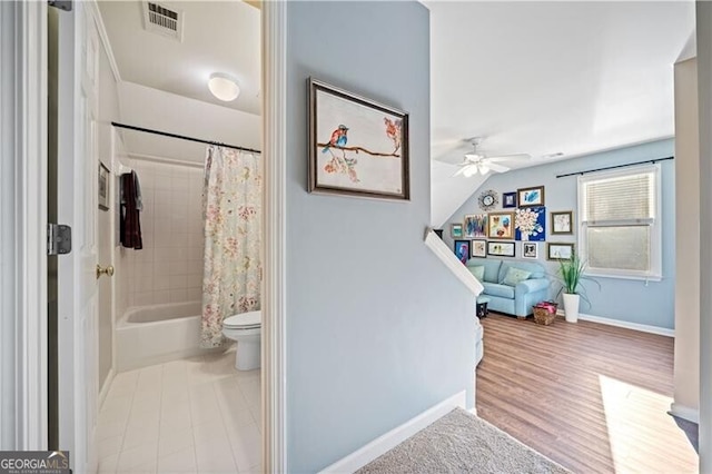 interior space with shower / tub combo, toilet, and ceiling fan