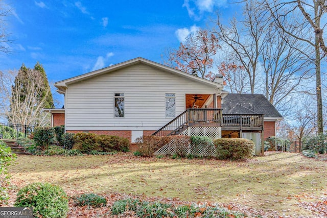 view of side of home with ceiling fan, a lawn, and a wooden deck