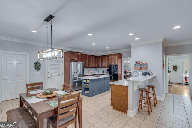 kitchen featuring pendant lighting, stainless steel fridge with ice dispenser, kitchen peninsula, and ornamental molding