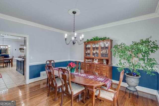 dining room with a notable chandelier, light wood-type flooring, and ornamental molding