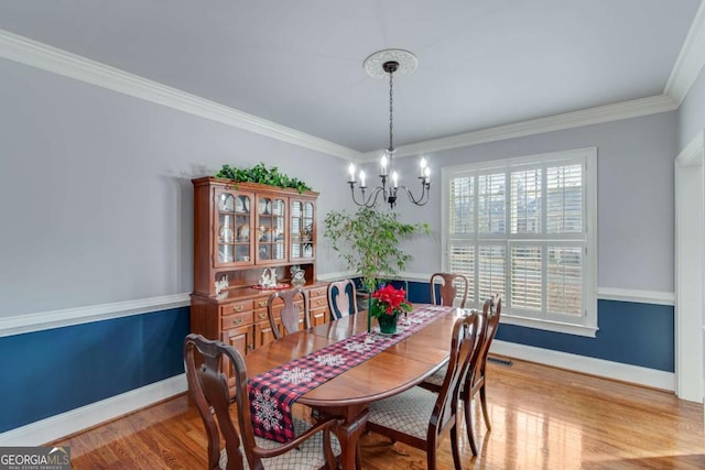 dining area featuring ornamental molding, light hardwood / wood-style flooring, and a notable chandelier