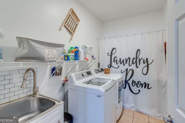 washroom featuring light tile patterned floors, washer and clothes dryer, and sink