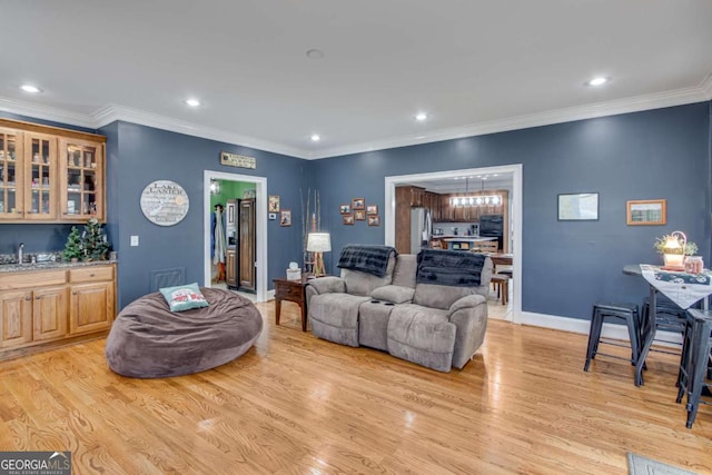 living room featuring light hardwood / wood-style floors, wet bar, and crown molding