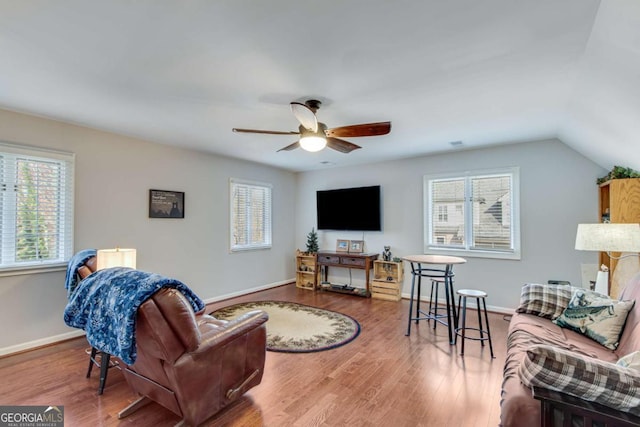 living room featuring hardwood / wood-style flooring, ceiling fan, and vaulted ceiling