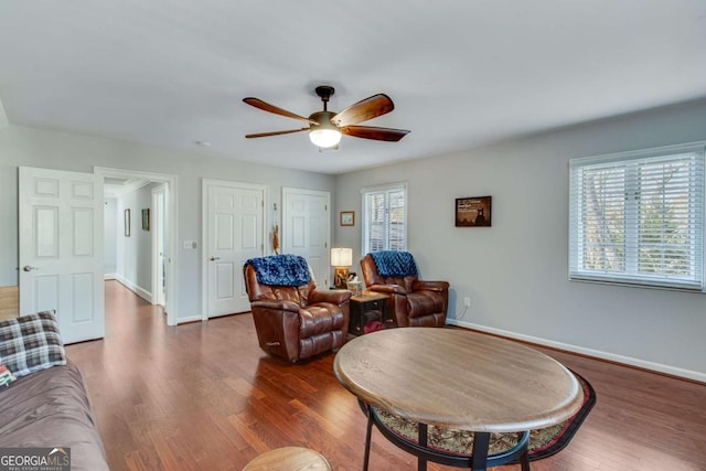 living area featuring a wealth of natural light, ceiling fan, and dark hardwood / wood-style flooring