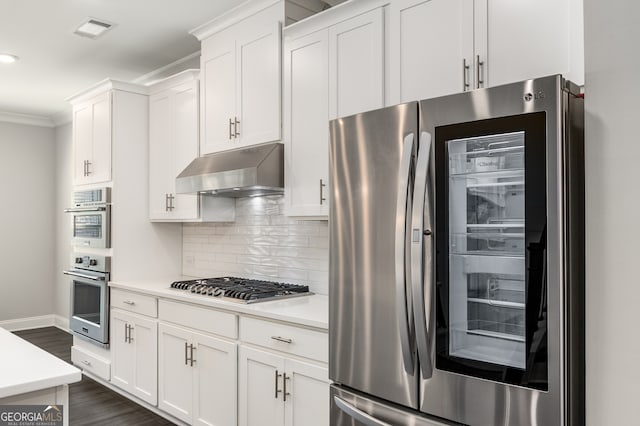 kitchen with stainless steel appliances, dark hardwood / wood-style floors, tasteful backsplash, ornamental molding, and white cabinets