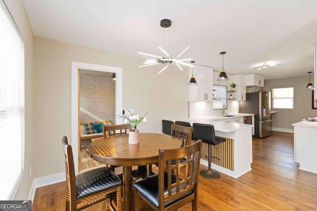 kitchen with white cabinetry, pendant lighting, decorative backsplash, appliances with stainless steel finishes, and hardwood / wood-style flooring