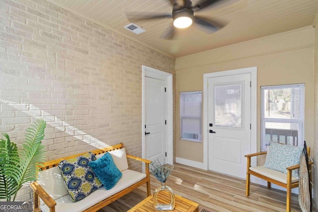 interior space with ceiling fan, brick wall, and light hardwood / wood-style flooring