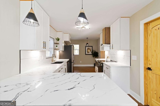 kitchen featuring sink, stainless steel range with electric stovetop, light stone counters, tasteful backsplash, and white cabinets