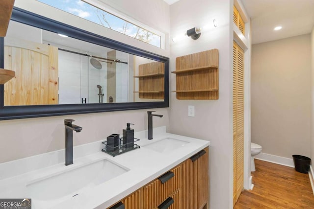 bathroom with vanity, wood-type flooring, a shower with shower door, and toilet