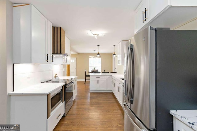 kitchen with kitchen peninsula, appliances with stainless steel finishes, decorative light fixtures, light stone counters, and white cabinetry