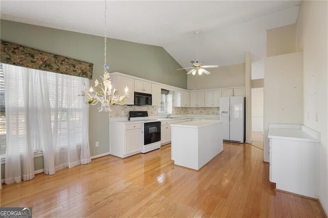 kitchen featuring a center island, white appliances, white cabinets, tasteful backsplash, and decorative light fixtures