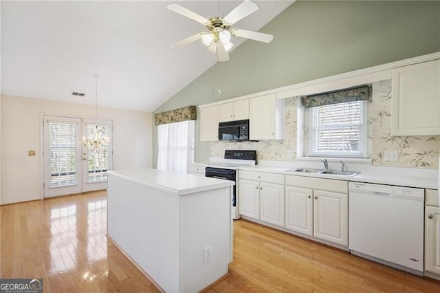 kitchen featuring pendant lighting, white dishwasher, white cabinets, sink, and electric range