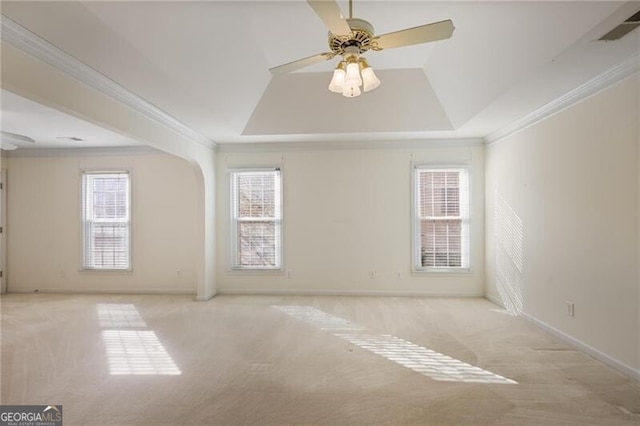 carpeted spare room with a tray ceiling, ceiling fan, and ornamental molding