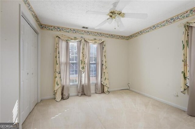 empty room featuring carpet flooring, ceiling fan, and a textured ceiling