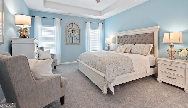 bedroom with ceiling fan, carpet floors, visible vents, baseboards, and a raised ceiling