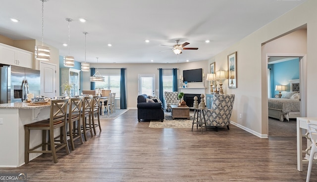 living room featuring dark wood-style flooring, a fireplace, recessed lighting, a ceiling fan, and baseboards