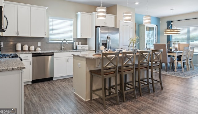 kitchen featuring dark wood-style floors, appliances with stainless steel finishes, a kitchen island, and a sink