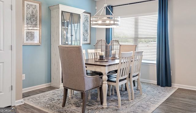 dining space featuring baseboards, wood finished floors, and a notable chandelier